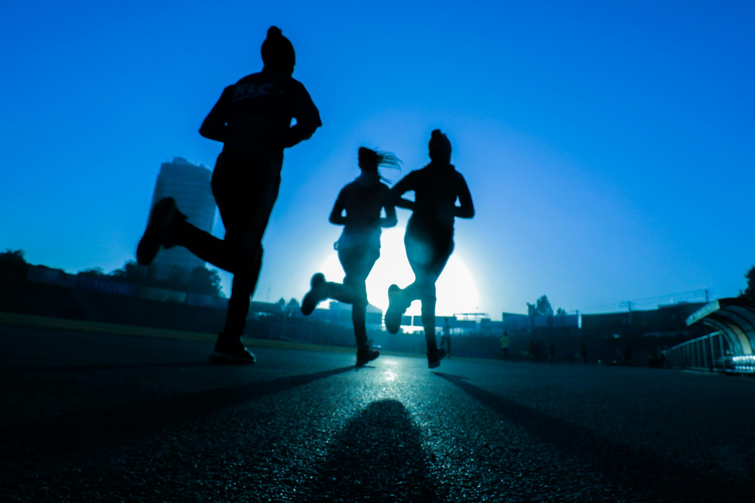 Drei Personen joggen bei Sonnenaufgang auf einer Straße, was an die Dynamik von App Store Optimierung erinnert.