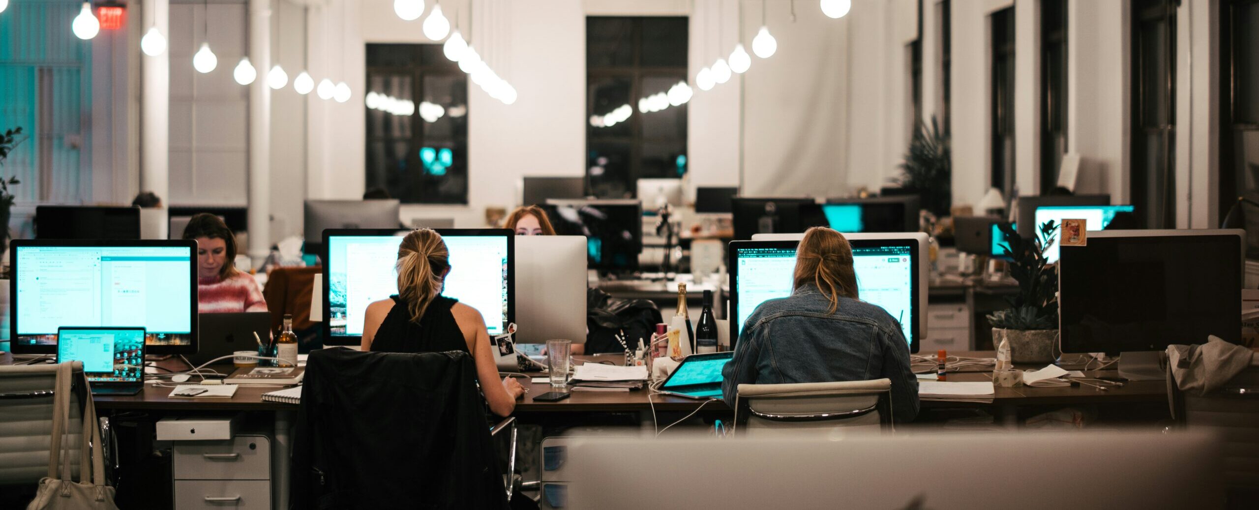 In einem modernen Büro arbeiten mehrere Personen konzentriert an Computern, was App Store Optimierung reflektiert.